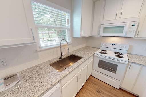 A kitchen with a granite countertop and white cabinets.