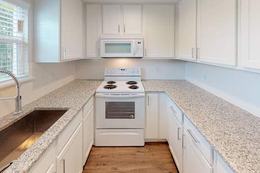 A white kitchen with a stove top oven and microwave.