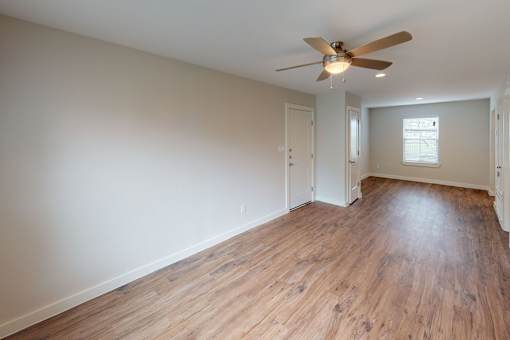 A room with a ceiling fan and wooden flooring.
