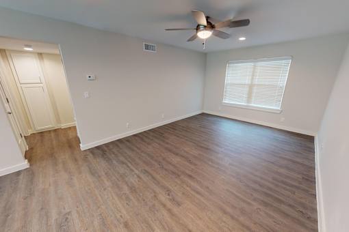 A room with a ceiling fan and wooden flooring.