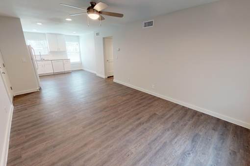 A room with a ceiling fan and wooden flooring.