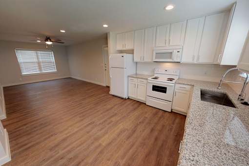 A kitchen with white appliances and wooden floors.