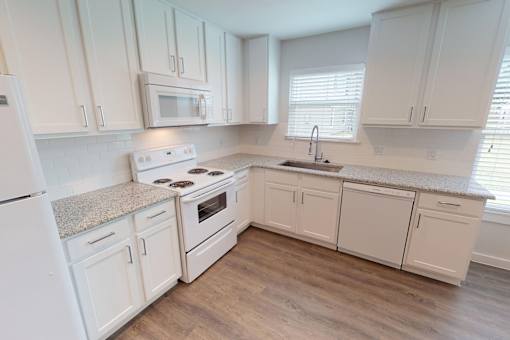 A kitchen with white cabinets and appliances.