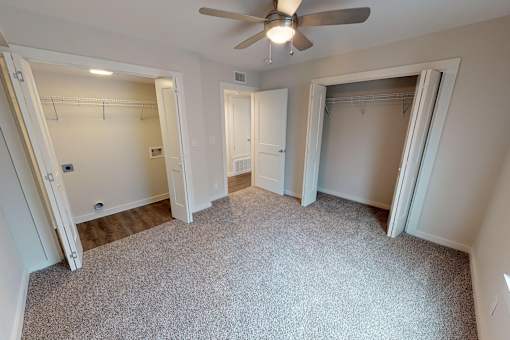 A room with a ceiling fan and carpeted floor.