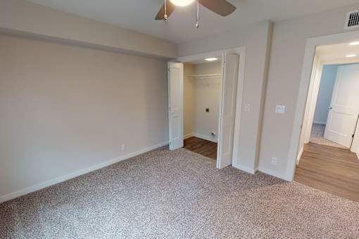 A room with a carpeted floor and a ceiling fan.