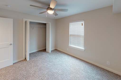 A room with a ceiling fan and a window with blinds.