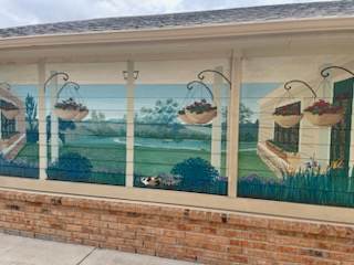 A mural on a wall depicts a serene garden scene with hanging baskets of fruit.