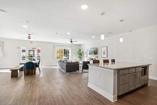 A spacious living room with a kitchen area in the background.