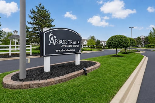 A sign for Arbor Trails Apartment Homes stands in a grassy area.