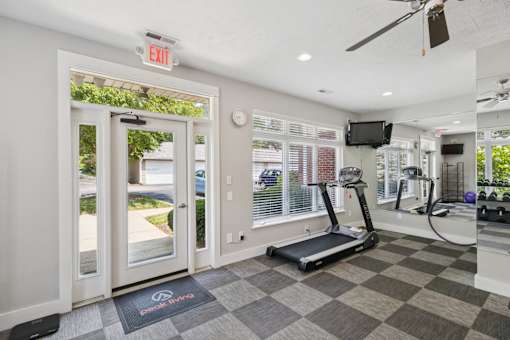 A gym with a treadmill, exercise bike, and a television.