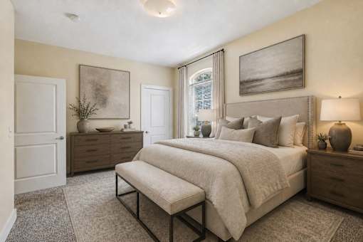 A bedroom with a large bed and a bench in front of it.