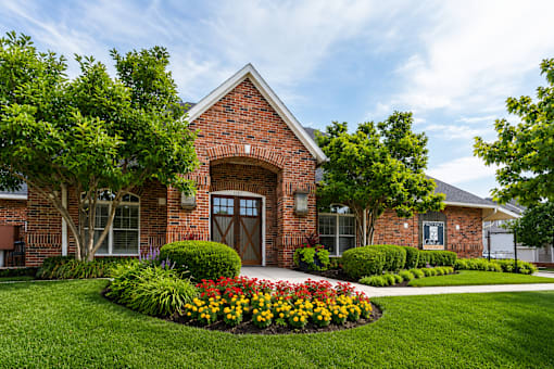 A brick building with a flower bed in front.