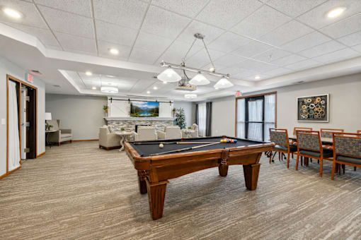 A room with a pool table and chairs.
