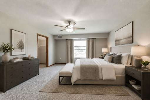 A bedroom with a large bed, a dresser, and a ceiling fan.