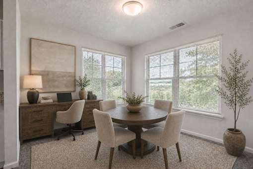 A room with a round table surrounded by chairs and a laptop on the desk.