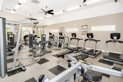 A gym with a variety of equipment including treadmills, stationary bikes, and weight machines.