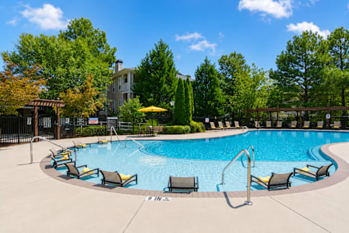 A swimming pool surrounded by lounge chairs and trees.