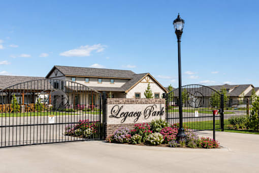 The Legacy Park sign is mounted on a black metal gate.