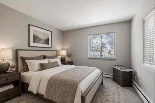 A bedroom with a large bed and a window with blinds.