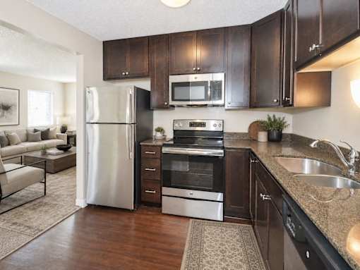 A kitchen with dark brown cabinets and a stainless steel refrigerator.