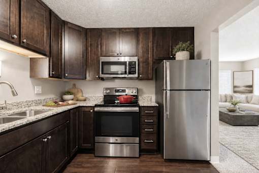 A modern kitchen with dark wood cabinets and stainless steel appliances.