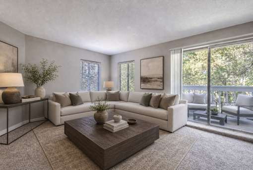 A living room with a white couch, a coffee table, and a balcony with chairs.