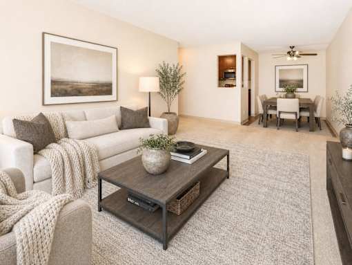 A living room with a white couch, a coffee table, and a painting on the wall.