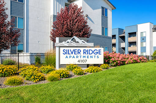Monument sign with mountain graphic and yellow flowers at Silver Ridge Apartments, Meridian