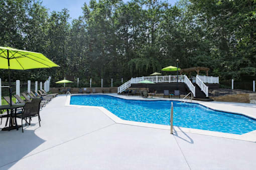 A pool with a white fence and trees in the background.