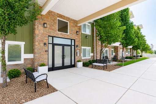 Apartment building entrance with stone accents and landscaping at The Ellison Apartments, Layton, UT