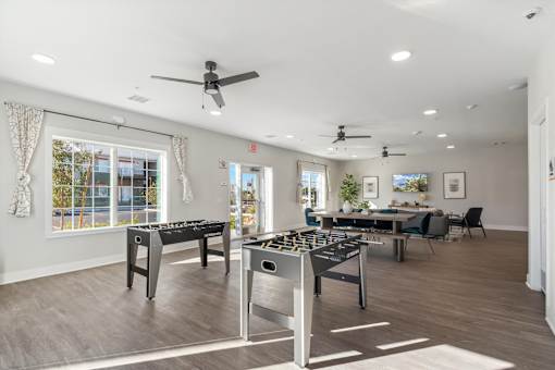 A spacious room with a foosball table and a pool table.