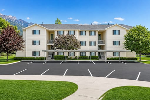A large apartment complex with a parking lot in front.