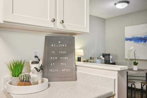 A sign that says "Welcome to your new home at the Felix Apartments" is displayed in a kitchen.
