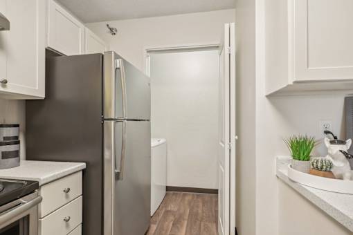 A kitchen with a black refrigerator and white cabinets.