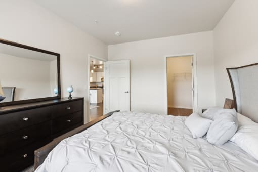a bedroom with a large white bed and a mirror