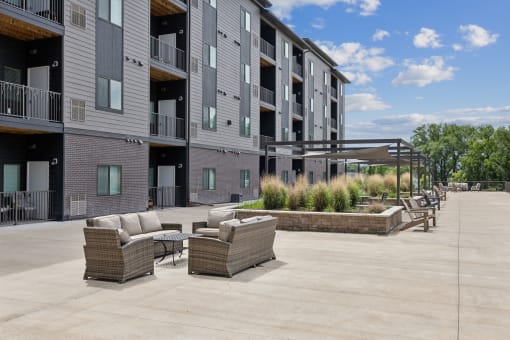 an outdoor patio with couches and chairs in front of a building
