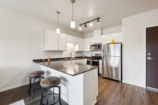 A modern kitchen with stainless steel appliances, a large island, and overhead lighting.