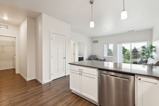an open kitchen and living room with a large counter top and a stainless steel refrigerator