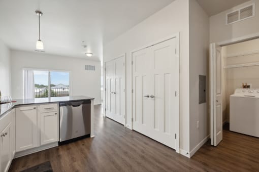 an empty kitchen with white cabinets and a white refrigerator and a sink