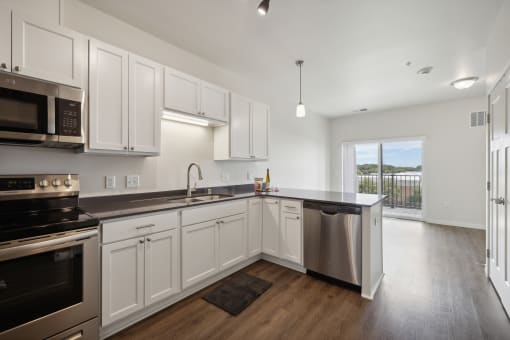 an empty kitchen with white cabinets and stainless steel appliances