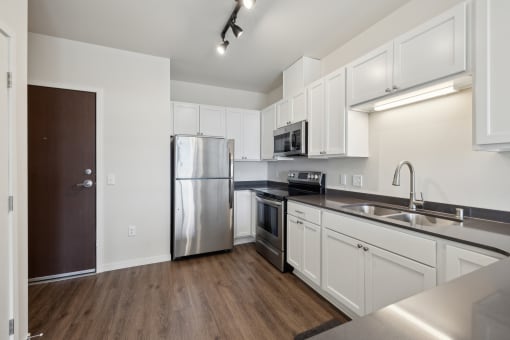 an empty kitchen with stainless steel appliances and white cabinetry
