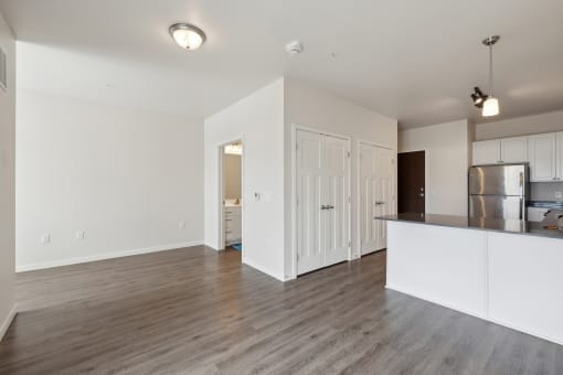 an empty living room and kitchen with white walls and wood flooring