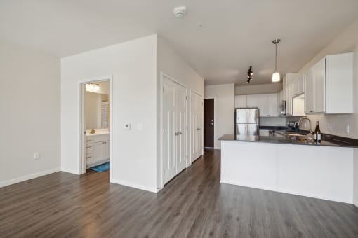 an open kitchen and living room with white walls and wood flooring