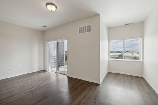 an empty living room with hard wood floors and a window