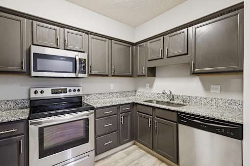 A kitchen with a stove, oven, microwave, and sink.