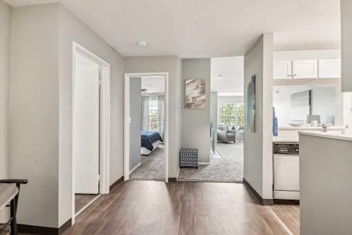 A modern kitchen with a dining area and a bedroom visible through the open door.