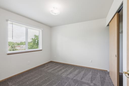 an empty living room with a large window and a carpet