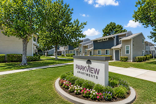 A sign that says Parkview Apartments is in front of some houses.
