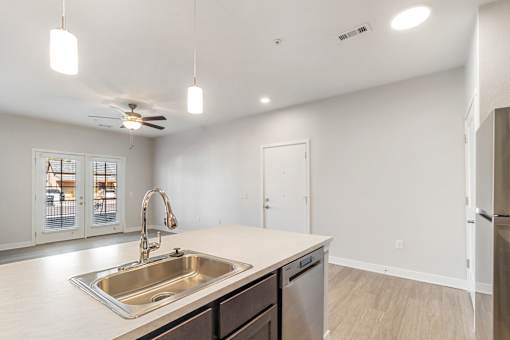 A kitchen with a sink, a refrigerator, and a ceiling fan.