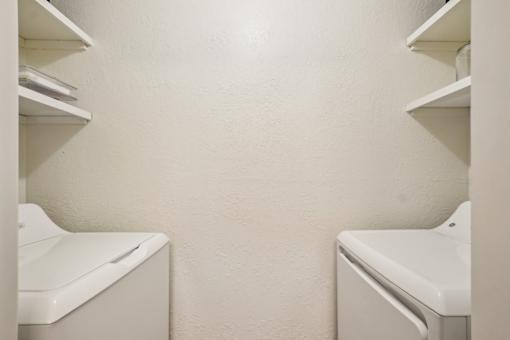Two white washing machines in a laundry room.